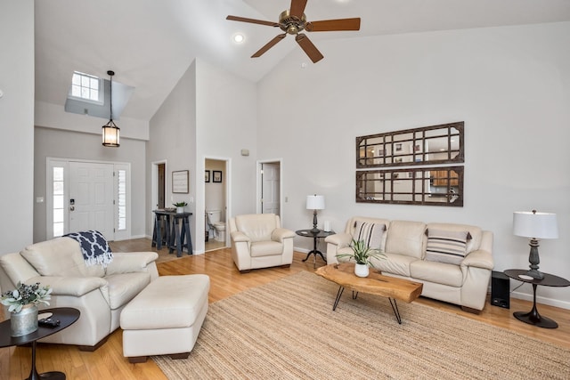 living room with ceiling fan, baseboards, high vaulted ceiling, and wood finished floors