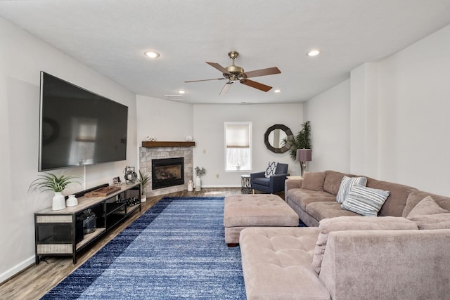 living room with wood finished floors, baseboards, recessed lighting, ceiling fan, and a stone fireplace