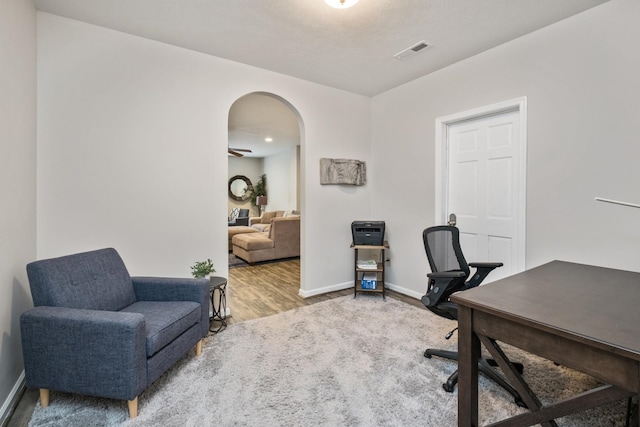 office space with visible vents, arched walkways, baseboards, and wood finished floors