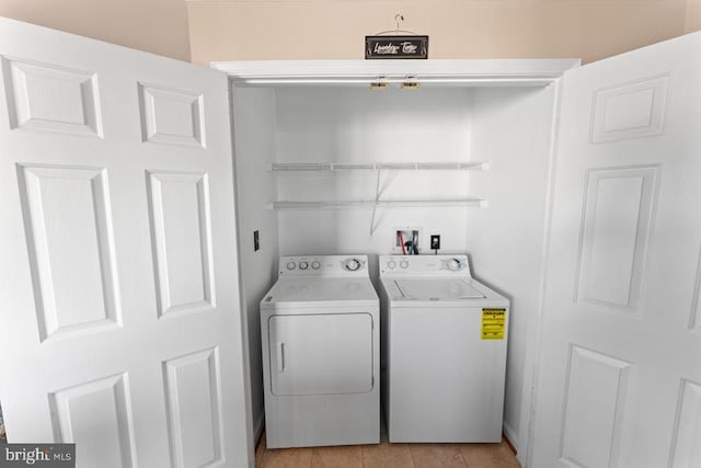 clothes washing area featuring light tile patterned floors, laundry area, and washer and clothes dryer