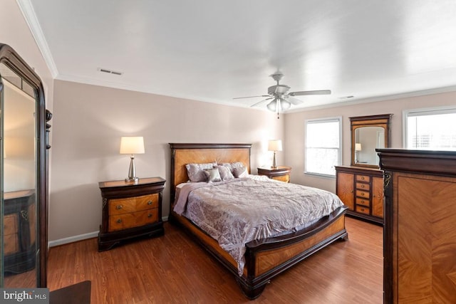 bedroom with a ceiling fan, visible vents, wood finished floors, baseboards, and ornamental molding