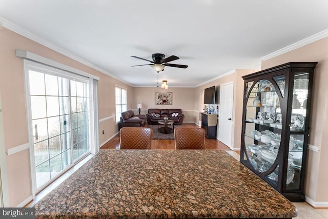 dining area featuring baseboards, a ceiling fan, light wood-style flooring, and crown molding