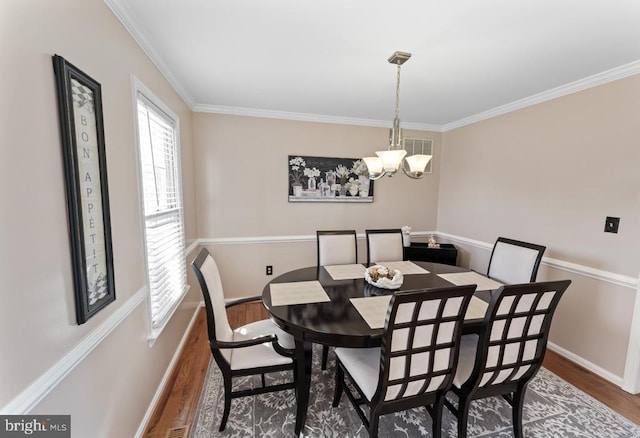 dining space featuring crown molding, a notable chandelier, wood finished floors, and baseboards