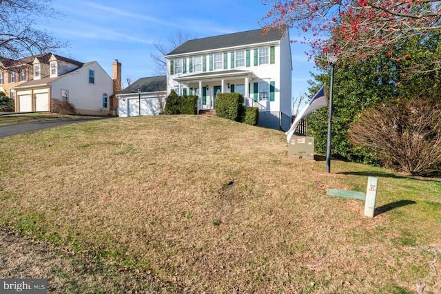 colonial-style house with a garage, covered porch, and a front yard