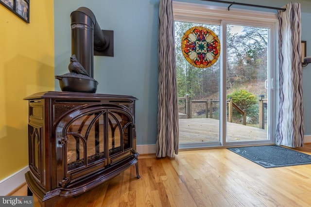 doorway featuring baseboards, wood finished floors, and a wood stove