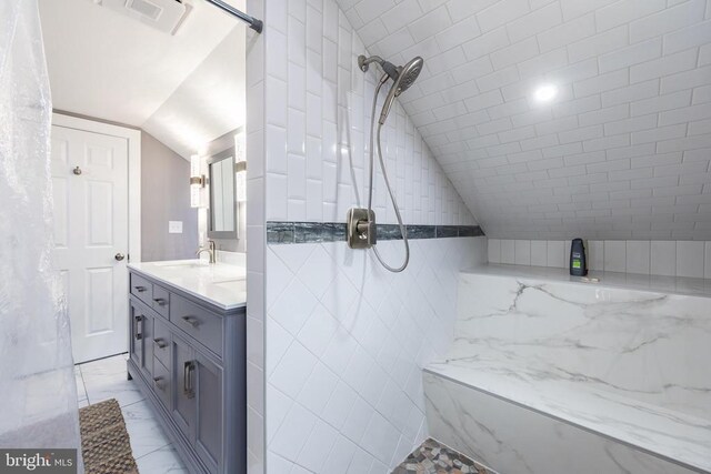 bathroom with a tile shower, marble finish floor, vaulted ceiling, visible vents, and vanity