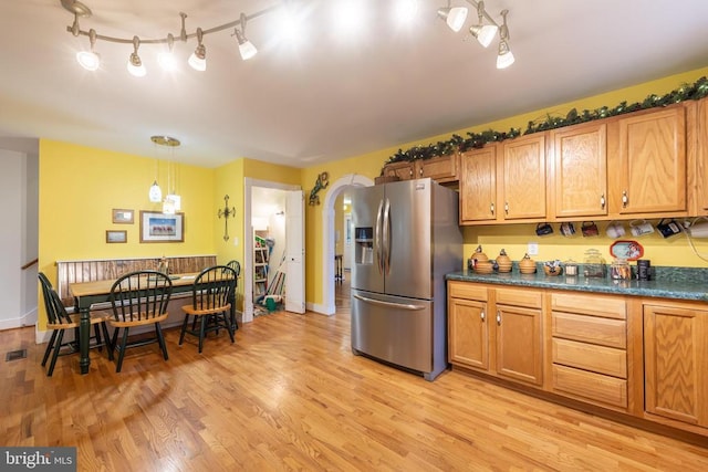 kitchen featuring dark countertops, light wood-style flooring, and stainless steel fridge with ice dispenser