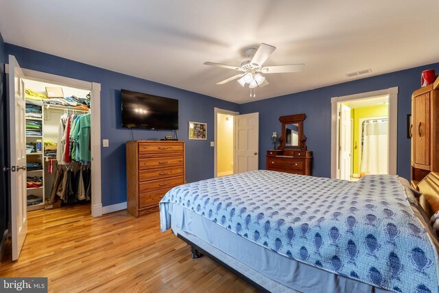 bedroom featuring visible vents, a walk in closet, light wood-style floors, a closet, and baseboards