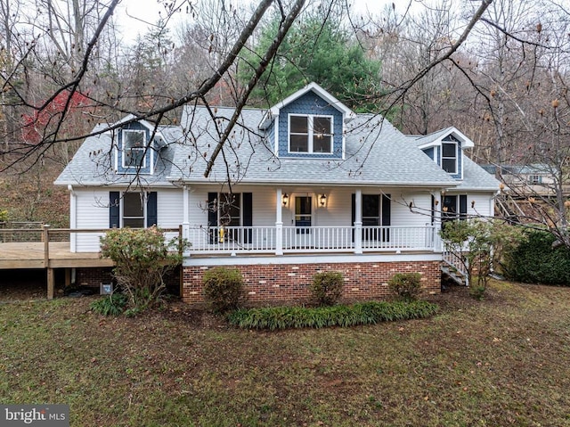 cape cod house with a porch, a shingled roof, and a front yard