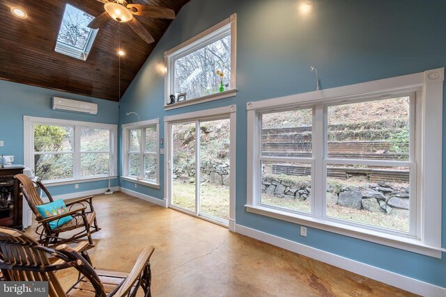 sunroom featuring high vaulted ceiling, an AC wall unit, concrete floors, a skylight, and baseboards
