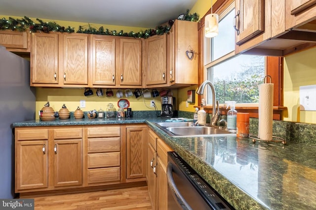 kitchen featuring dark countertops, dishwashing machine, a sink, light wood-style floors, and freestanding refrigerator