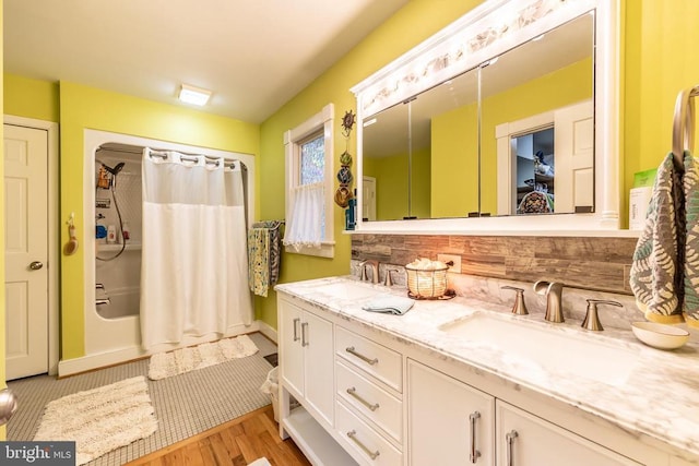 bathroom featuring decorative backsplash, baseboards, a sink, and double vanity