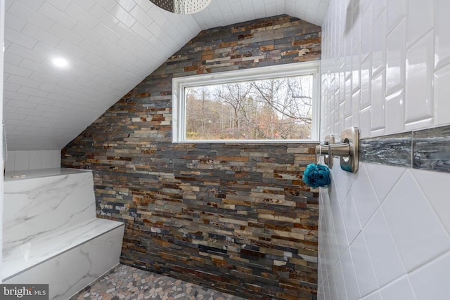 bathroom featuring vaulted ceiling and a tile shower