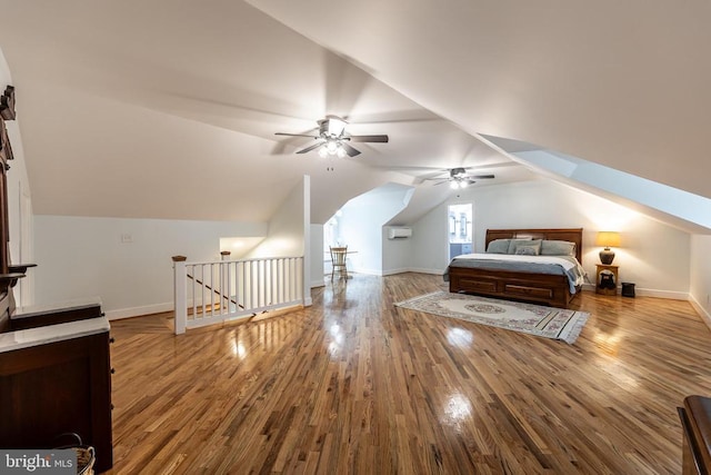 unfurnished bedroom featuring baseboards, lofted ceiling, wood finished floors, and a wall unit AC
