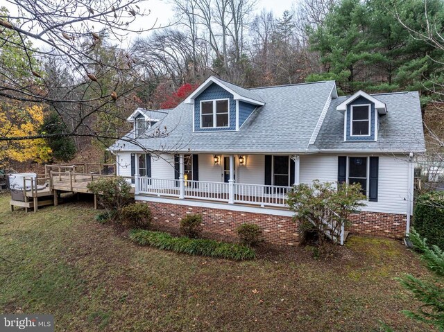 view of front of home with a porch, a shingled roof, and a front yard