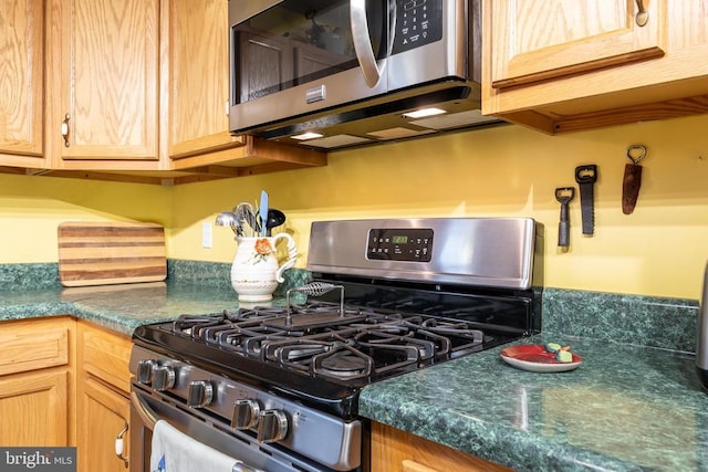 kitchen featuring dark countertops, stainless steel appliances, and light brown cabinetry