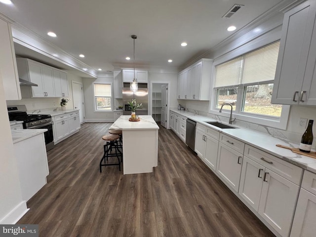 kitchen with ornamental molding, appliances with stainless steel finishes, white cabinetry, and a sink