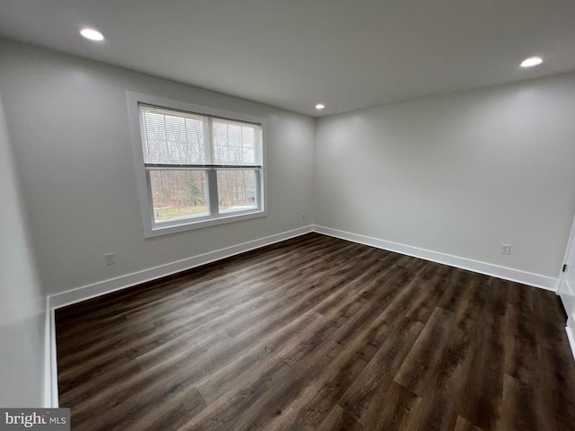 spare room featuring dark wood-style floors, recessed lighting, and baseboards