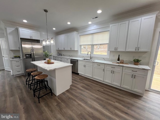 kitchen featuring visible vents, a sink, a center island, stainless steel appliances, and a breakfast bar area