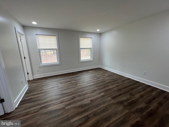 unfurnished room featuring dark wood finished floors, a healthy amount of sunlight, and baseboards