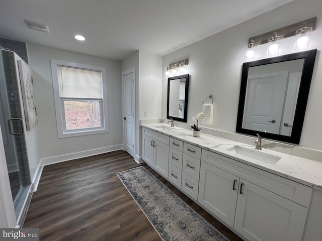 bathroom featuring a sink, baseboards, wood finished floors, and double vanity