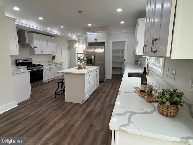 kitchen featuring a center island, wall chimney range hood, dark wood finished floors, stainless steel appliances, and a sink