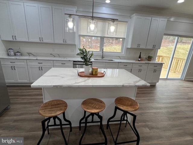 kitchen featuring a breakfast bar, dark wood-style floors, white cabinetry, and a sink