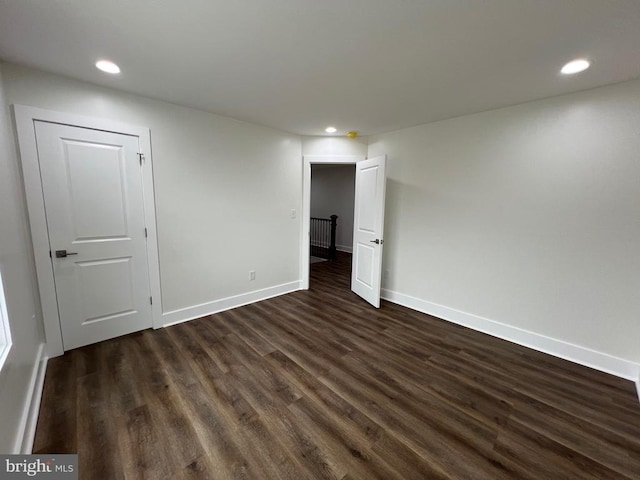 empty room featuring recessed lighting, dark wood-type flooring, and baseboards