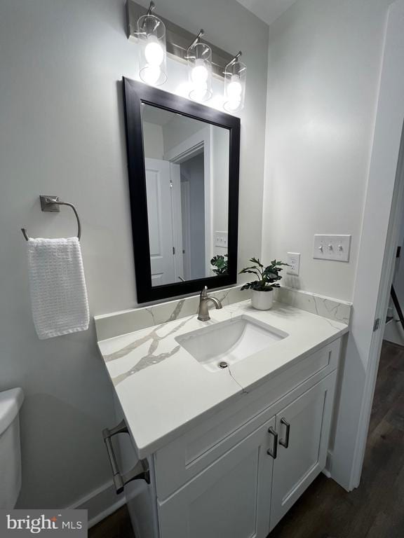 half bath featuring toilet, vanity, and baseboards