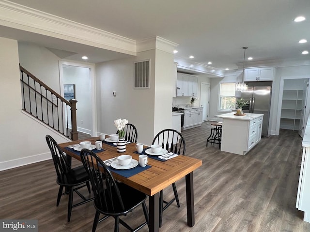 dining area featuring dark wood-type flooring, baseboards, visible vents, and ornamental molding