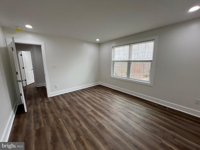 spare room with recessed lighting, visible vents, baseboards, and dark wood-style floors