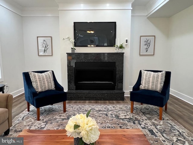 sitting room with baseboards, wood finished floors, ornamental molding, and a high end fireplace