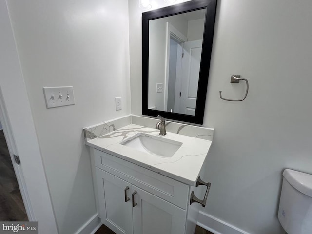 bathroom featuring toilet, vanity, and baseboards