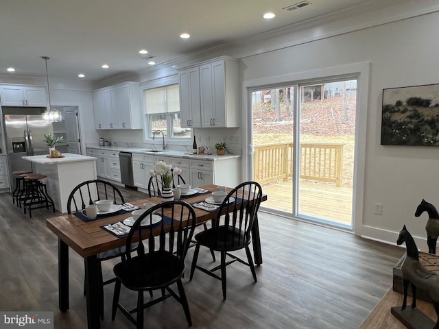 dining space featuring wood finished floors, visible vents, baseboards, recessed lighting, and crown molding