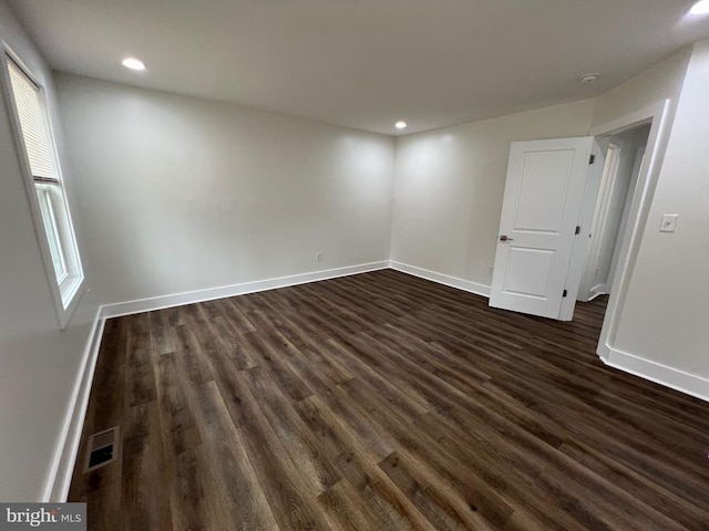 empty room featuring dark wood finished floors, visible vents, recessed lighting, and baseboards