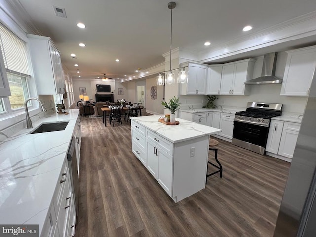 kitchen featuring gas stove, a sink, dark wood-type flooring, wall chimney exhaust hood, and open floor plan