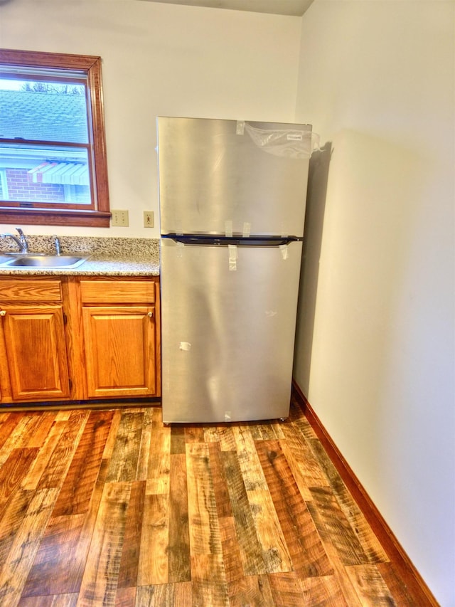 kitchen with sink, hardwood / wood-style flooring, and stainless steel refrigerator