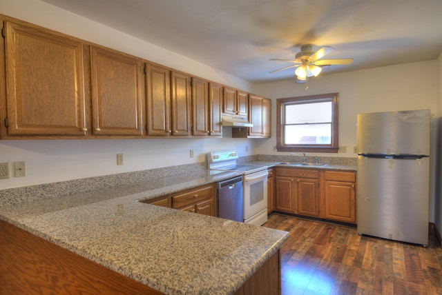 kitchen featuring dark hardwood / wood-style floors, sink, light stone counters, kitchen peninsula, and stainless steel appliances