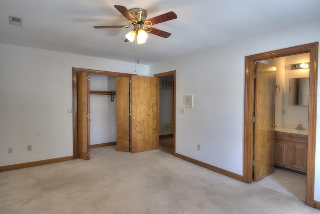 unfurnished bedroom featuring sink, light carpet, ensuite bath, and a closet