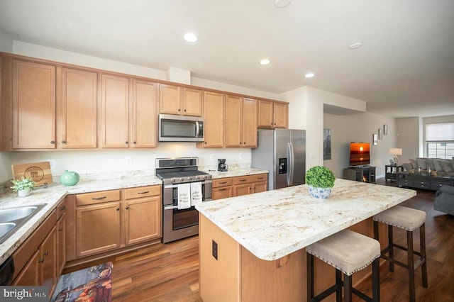 kitchen featuring a kitchen island, dark wood finished floors, recessed lighting, appliances with stainless steel finishes, and a kitchen breakfast bar