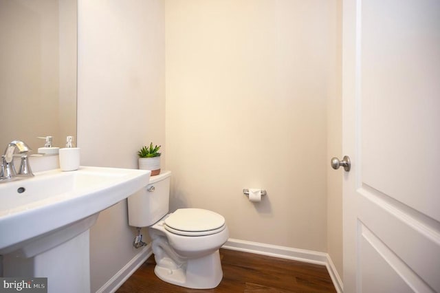 bathroom with baseboards, toilet, and wood finished floors