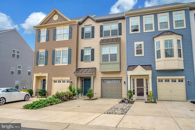 townhome / multi-family property featuring metal roof, an attached garage, driveway, and a standing seam roof