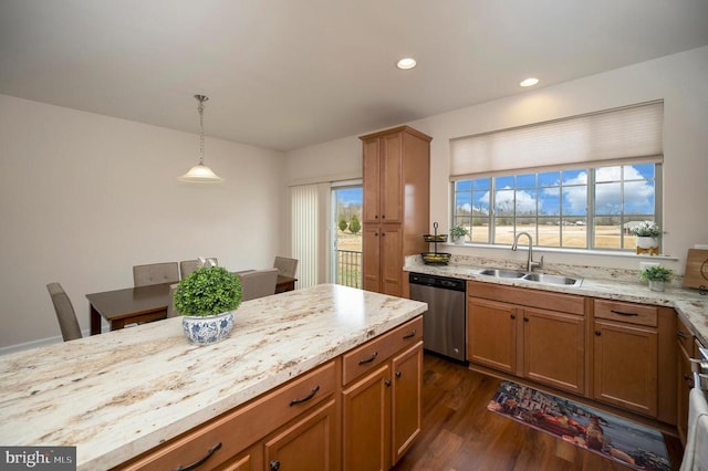 kitchen with decorative light fixtures, dark wood-style flooring, brown cabinets, stainless steel dishwasher, and a sink