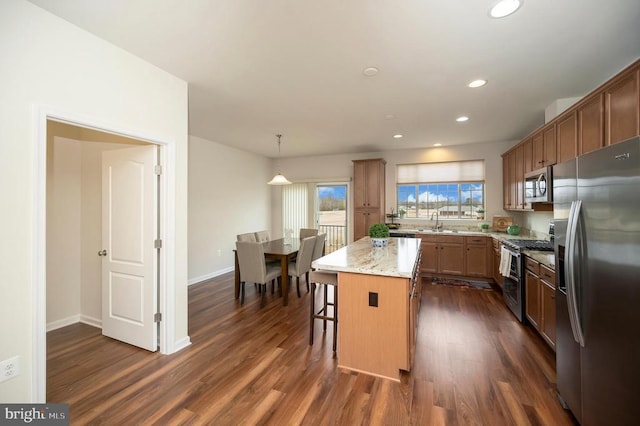 kitchen featuring dark wood-type flooring, light stone counters, a center island, recessed lighting, and appliances with stainless steel finishes