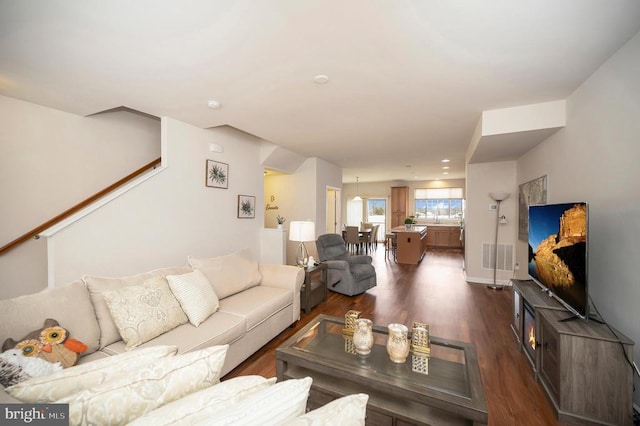 living area with stairway, baseboards, and dark wood-style flooring