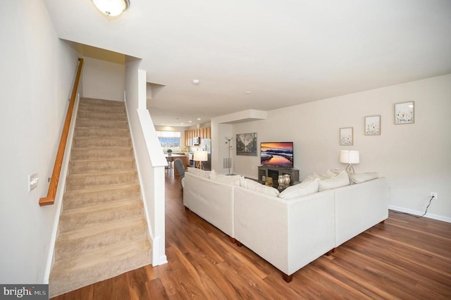 living room featuring baseboards, wood finished floors, and stairs