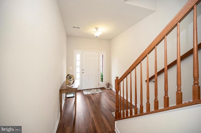 entrance foyer with visible vents, stairway, baseboards, and wood finished floors