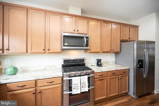 kitchen with dark wood finished floors, light stone counters, brown cabinetry, and appliances with stainless steel finishes