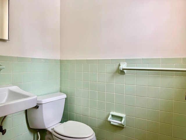 bathroom featuring tile walls and toilet