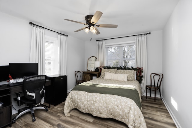 bedroom with multiple windows, wood-type flooring, and ceiling fan